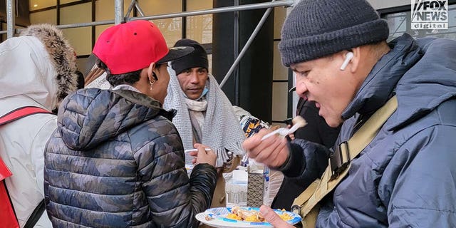 Migrants are seen outside the Watson Hotel in Midtown Manhattan, Monday, Jan. 30, 2023. Some slept on the street rather than be relocated to the Brooklyn Cruise Terminal over the weekend.