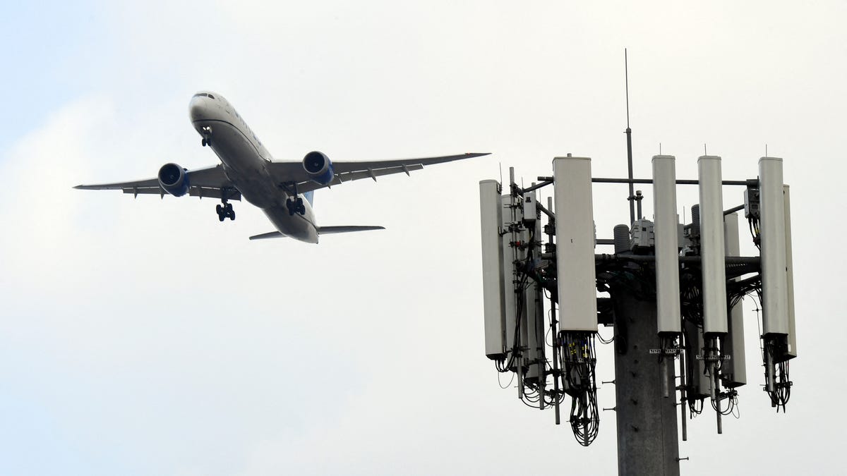 A passenger plan flies over a cell signal tower.