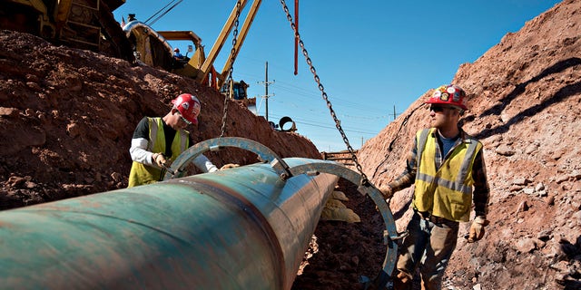 Workers remove a large clamp from a section of pipe during construction of part of the Keystone XL Pipeline Project in March 2013.