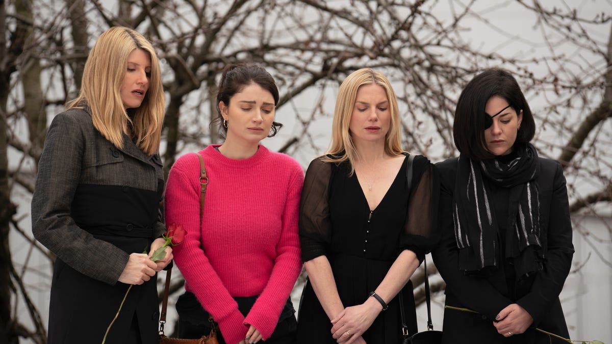 Four sisters standing over a funeral casket