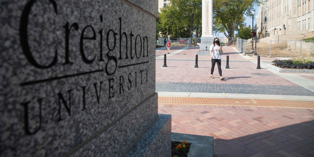 FILE - Students walk across 24th Street after the 24th Street dedication and ribbon cutting on the Creighton University campus in Omaha, Neb., Thursday, Sept. 24, 2020. The Nebraska Supreme Court on Friday, Aug. 12, 2022, has dismissed an appeal by a handful of Creighton University students seeking to be exempt from the school's COVID-19 vaccine mandate last year, arguing that getting the shots would violate their religious beliefs against abortion. (Lily Smith/Omaha World-Herald via AP)
