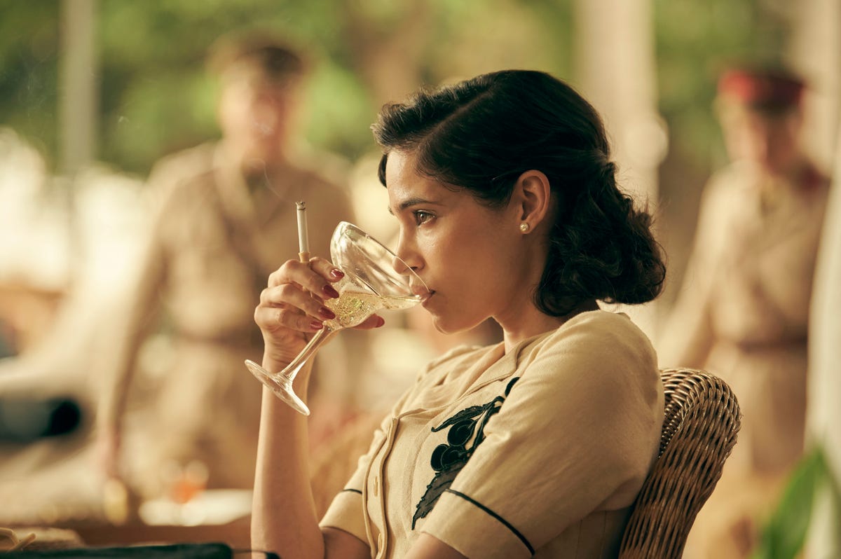 Sofia Boutella sips from a champagne saucer in Rogue Heroes.