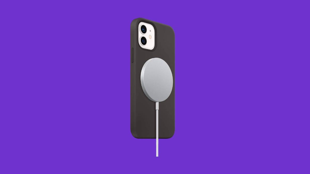 A MagSafe wireless charger attached to the back of an iPhone against a purple background.
