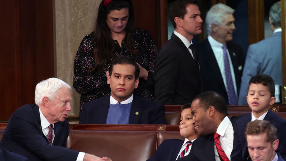 George Santos sitting in a crowd of people