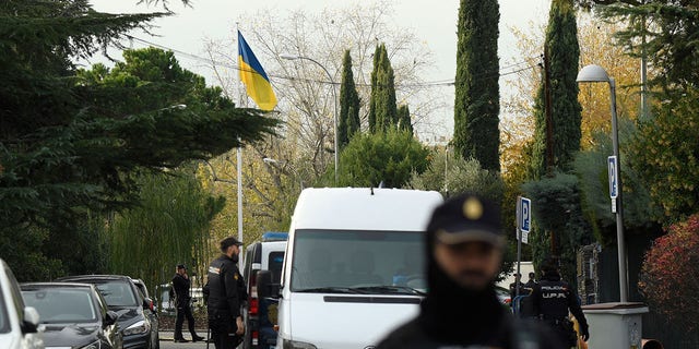 Spanish policemen stand next to an Ukrainian flag while securing the area after a letter bomb explosion at Ukraine's embassy in Madrid on November 30, 2022. 
