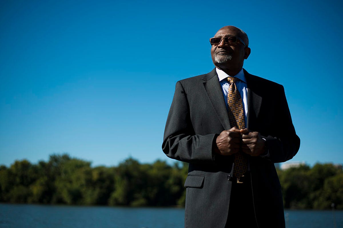 Robert Bullard in suit and tie, standing next to a river