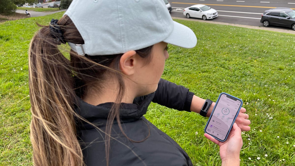 A woman looks at her Fitbit steps total on her phone