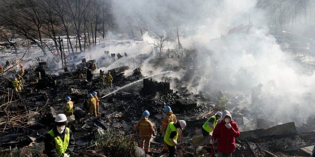 Firefighters and rescue workers clean up the site of a fire at Guryong village in Seoul, South Korea, Friday, Jan. 20, 2023. A fire spread through a neighborhood of densely packed, makeshift homes in South Korea's capital Friday morning. 