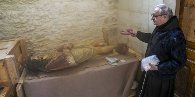 A priest stands by a damaged statue of Jesus in the Church of the Flagellation in Jerusalem's Old City, Thursday, Feb. 2, 2023.