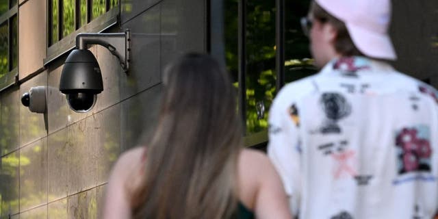 People walk past a security camera in Melbourne on Feb. 9, 2023.