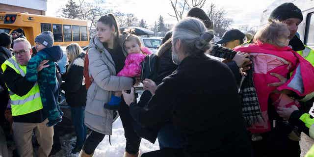 Parents and their children are loaded onto a warming bus after a city bus crashed into a daycare center in Laval, Quebec, on Feb. 8, 2023. 