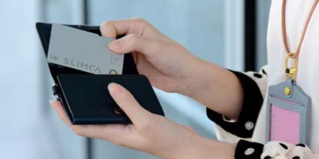 A woman is pulling the Slimca recording card out of her wallet. 