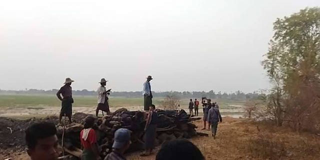 Men stand over a funeral pyre in Tar Taing village as they prepare to cremate bodies of those found dead in Burma on March 2, 2023. 