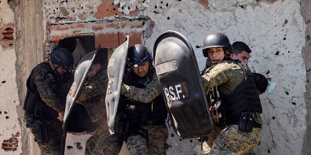 Police in riot gear protect a suspected gunman from his neighbors after an 11-year-old boy was killed in Rosario, Argentina, on March 6, 2023. 