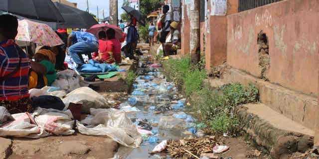 Vendors selling clothes and other merchandise in the city of Lilongwe, Malawi. Behind them is polluted water. Poor drainage facilities are a problem in the cholera infested country.