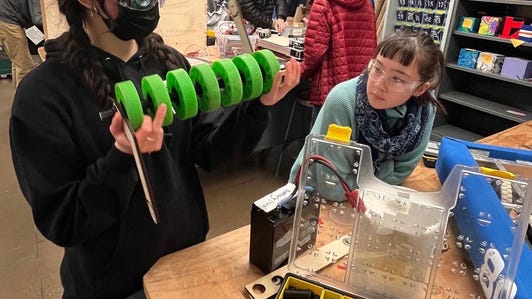 Here are Helena Young, a mechanical lead (left) and Ava Grochowski, a branding and design lead, inspecting robot parts.