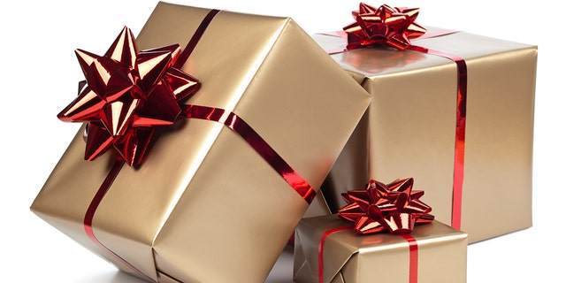 Gold gift boxes with red ribbon on white. A man in India rigged a music sound system with explosives and hid it among the wedding gifts for his former lover and her groom, who was killed. 