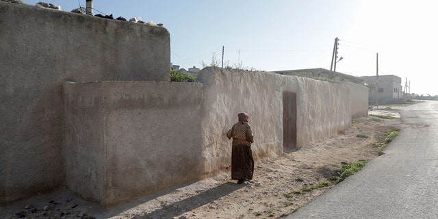 A woman walks past a house, following a US helicopter raid on an Islamic State group leader, in Soueida near Jarablus, in the north-east of Syria's Aleppo province, on April 17, 2023. 