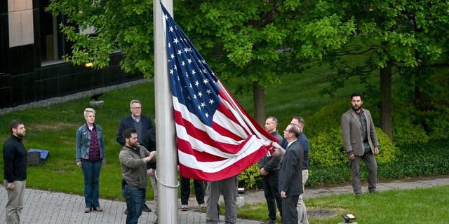 TOPSHOT - Employees rise up the flag outside the U.S. embassy in Kyiv on May 18, 2022, as the embassy reopens after being closed for three months due to the Russian invasion. 