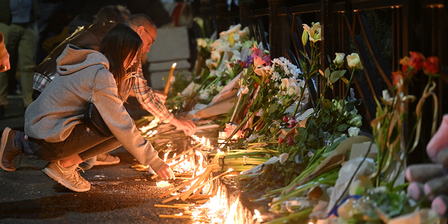 Students lay out candles on a memorial