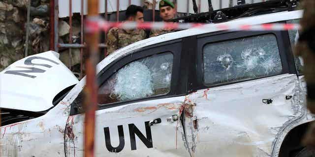  Lebanese soldiers look at a destroyed car