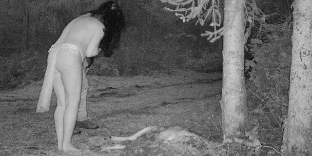 woman and man standing over deer carcass