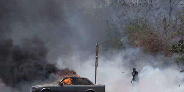 A demonstrator walks through smoke of tear gas 