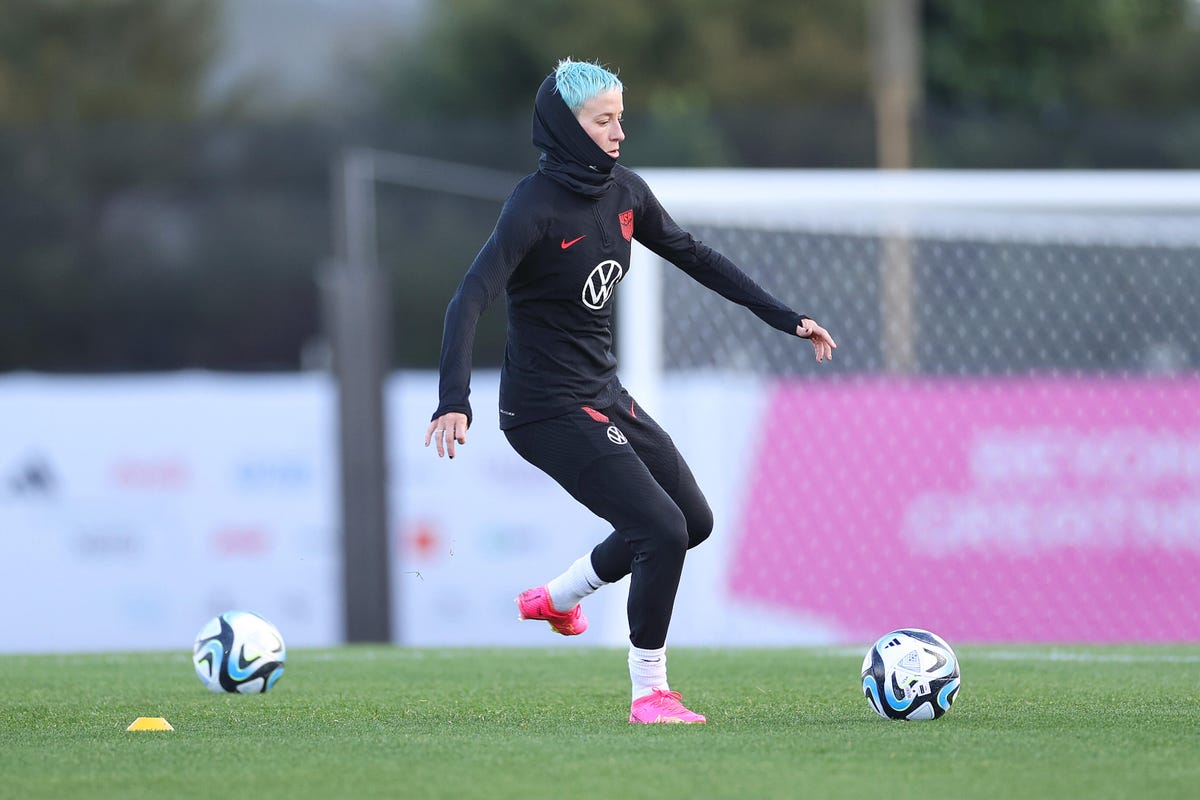 Megan Rapinoe with blue hair kicking a soccer ball