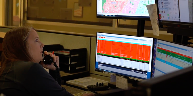911 operator on phone, looking at monitor