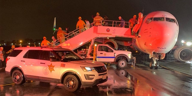 Firefighters guide passengers of an Alaska Airlines plane