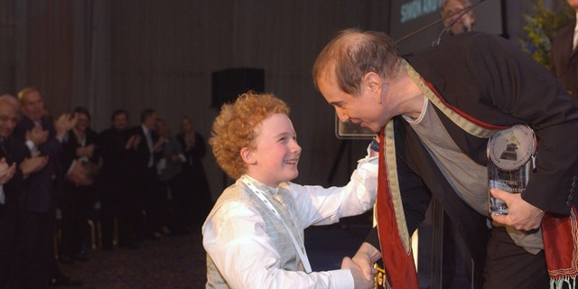 Paul Simon leaning down to Art Garfunkel Jr.