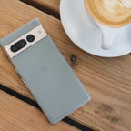 Pixel 7 Pro face down on a wooden table next to a cup of coffee