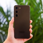 back of Samsung Galaxy S23 phone, held up in front of a plant