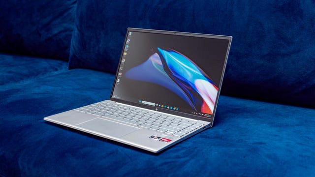 The 2023 HP Pavilion Aero 13 laptop open and facing to the right and sitting on a dark blue couch.