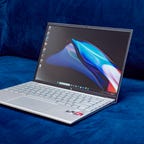 The 2023 HP Pavilion Aero 13 laptop open and facing to the right and sitting on a dark blue couch.