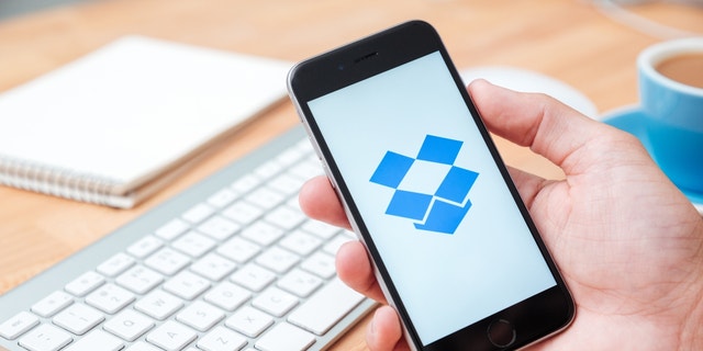 Person holding up their phone with the Dropbox app open.