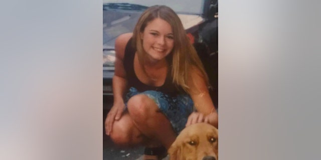 Christie Wilson kneeling down in a denim skirt and a brown tank top