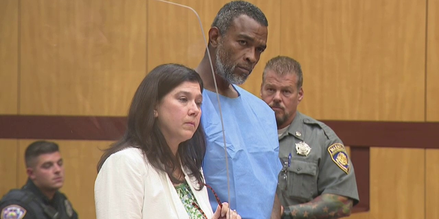 Winston Tate in blue jumpsuit with lawyer in court