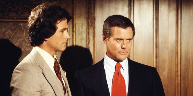 Patrick Duffy in a tan suit next to Larry Hagman in a dark blazer and red tie