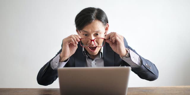 Man looking at his laptop in a shocked manner.