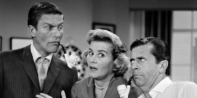 Rose Marie shrugging her arms as Dick Van Dyke and Morey Amerstam make funny faces