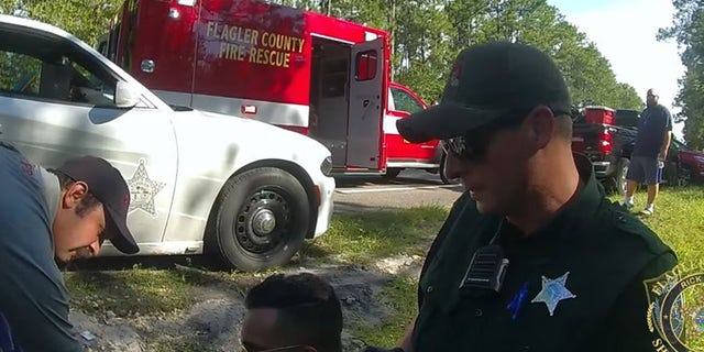 deputy on ground with ambulance behind him