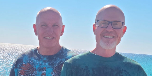 Herbert Swilley and Tim Smith pose together at the waterfront, backlit, wearing T-shirts
