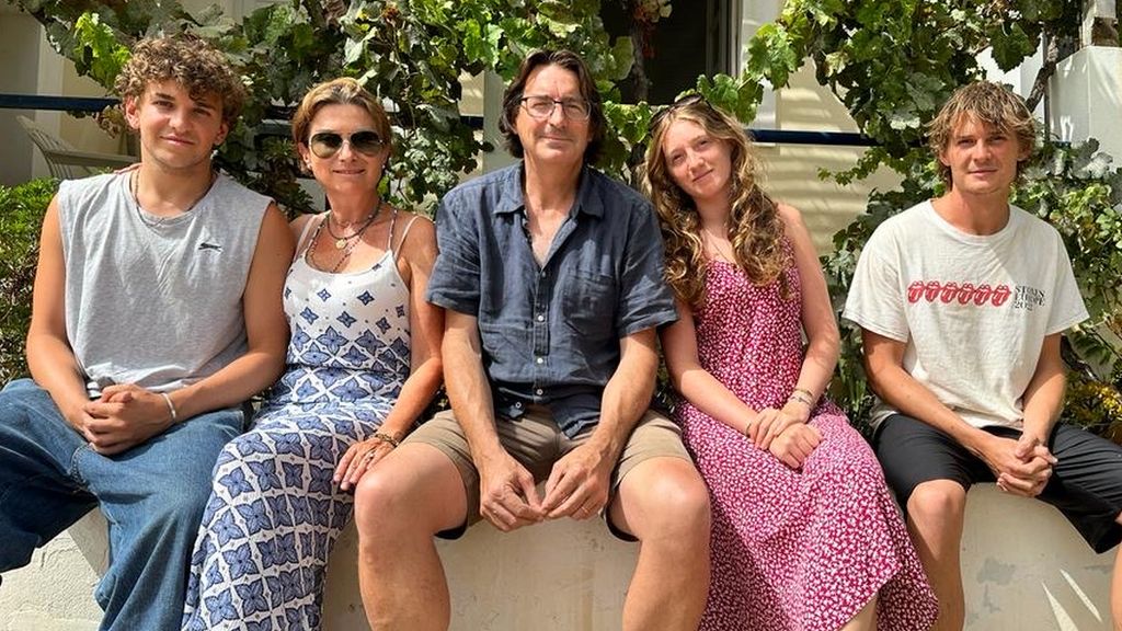 a family of five sit on a wall