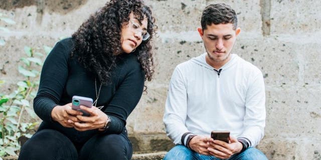 Woman looking at a man's phone while he's on it.