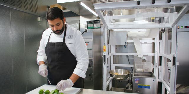 Photo of a chef working on mise en place while Chippy prepares tortilla chips in the background.