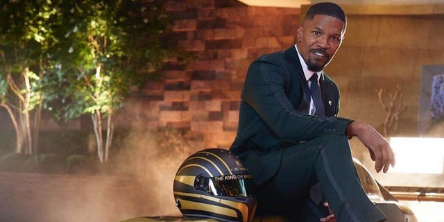 jamie foxx in black suit sitting on sports car for betmgm ad