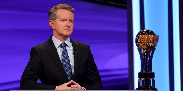 Ken Jennings looks serious with his hands together behind the podium during "Jeopardy"