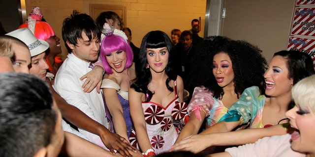 Katy Perry and her crew gathered together backstage in a huddle. Tasha Layton is wearing a hot pink bob wig.