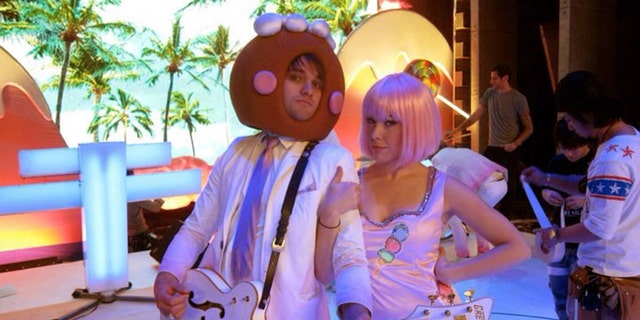 Tasha Layton wearing a hot pink wig and a playful costume next to a musician wearing a mask for a Katy Perry concert